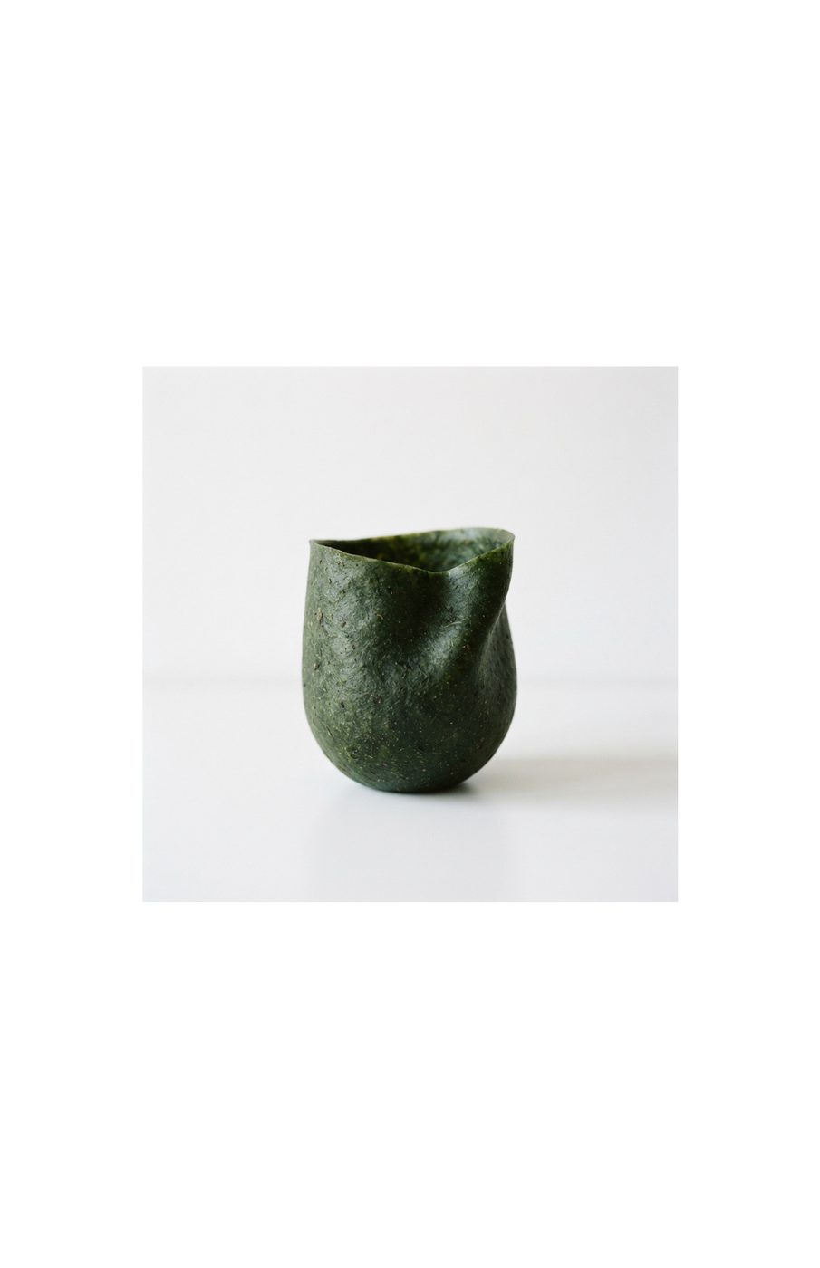A single dark green seaweed-grown vessel with an organic tapered form